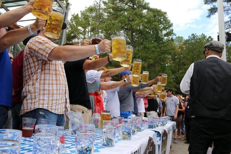 Stein hoisting participants hold up glasses of beer