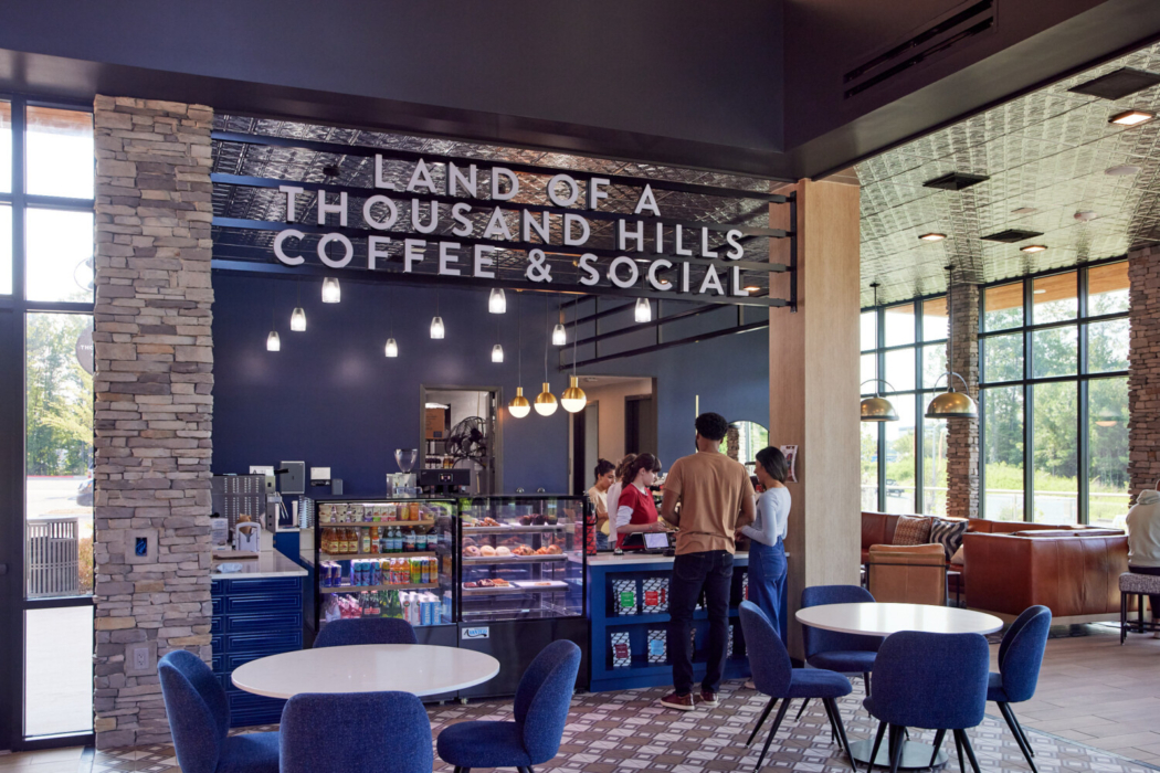 People smiling and enjoying coffee inside Novel Morrisville coffee shop, surrounded by warm lighting and a modern, inviting atmosphere.